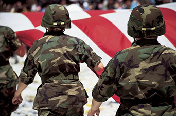 Image of uniformed military members with a flag
